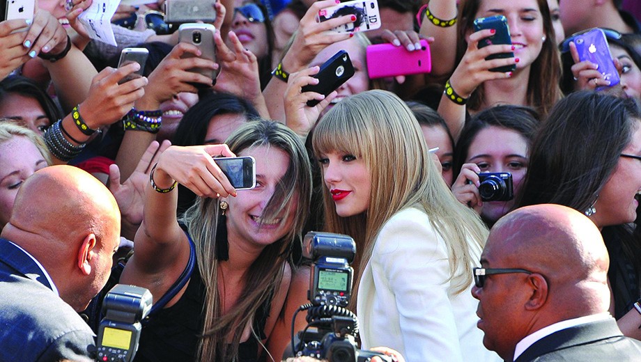 Paula Harper, AB’10, studies the dynamics of online fan communities like the one surrounding Taylor Swift, seen here posing for a selfie with a fan.