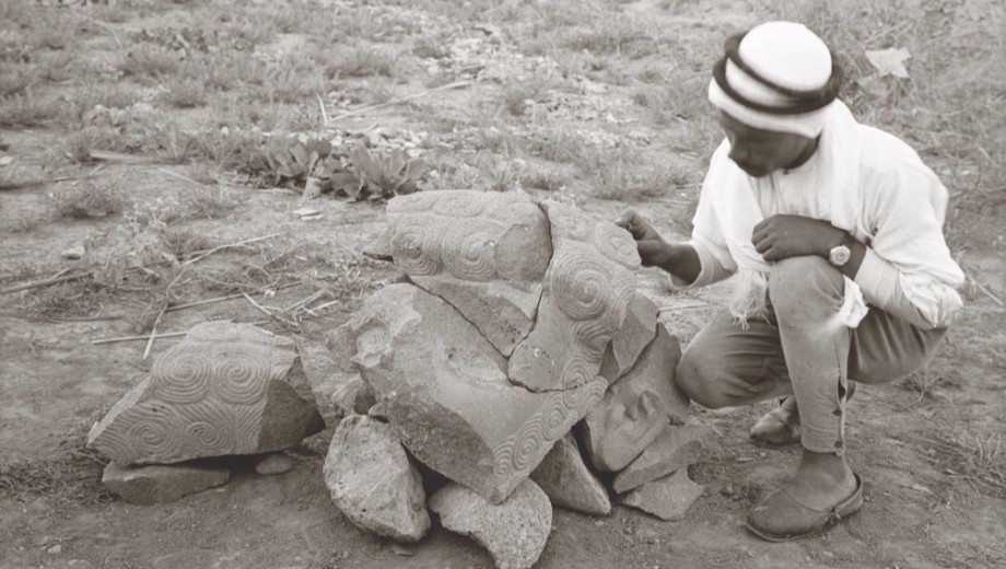 An archaelogist examines an ancient sculpture.